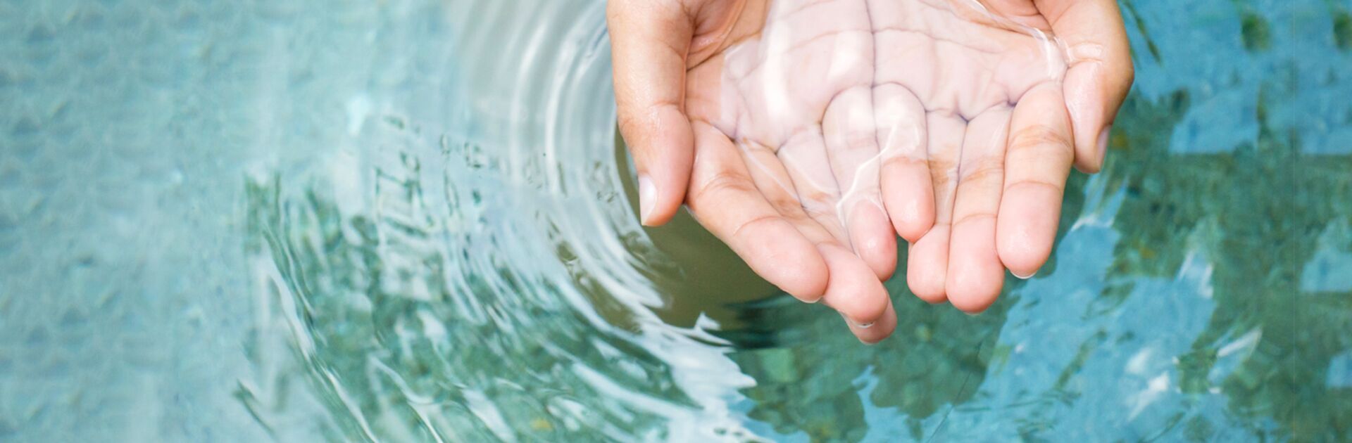 Hände schöpfen Wasser aus einer Quelle