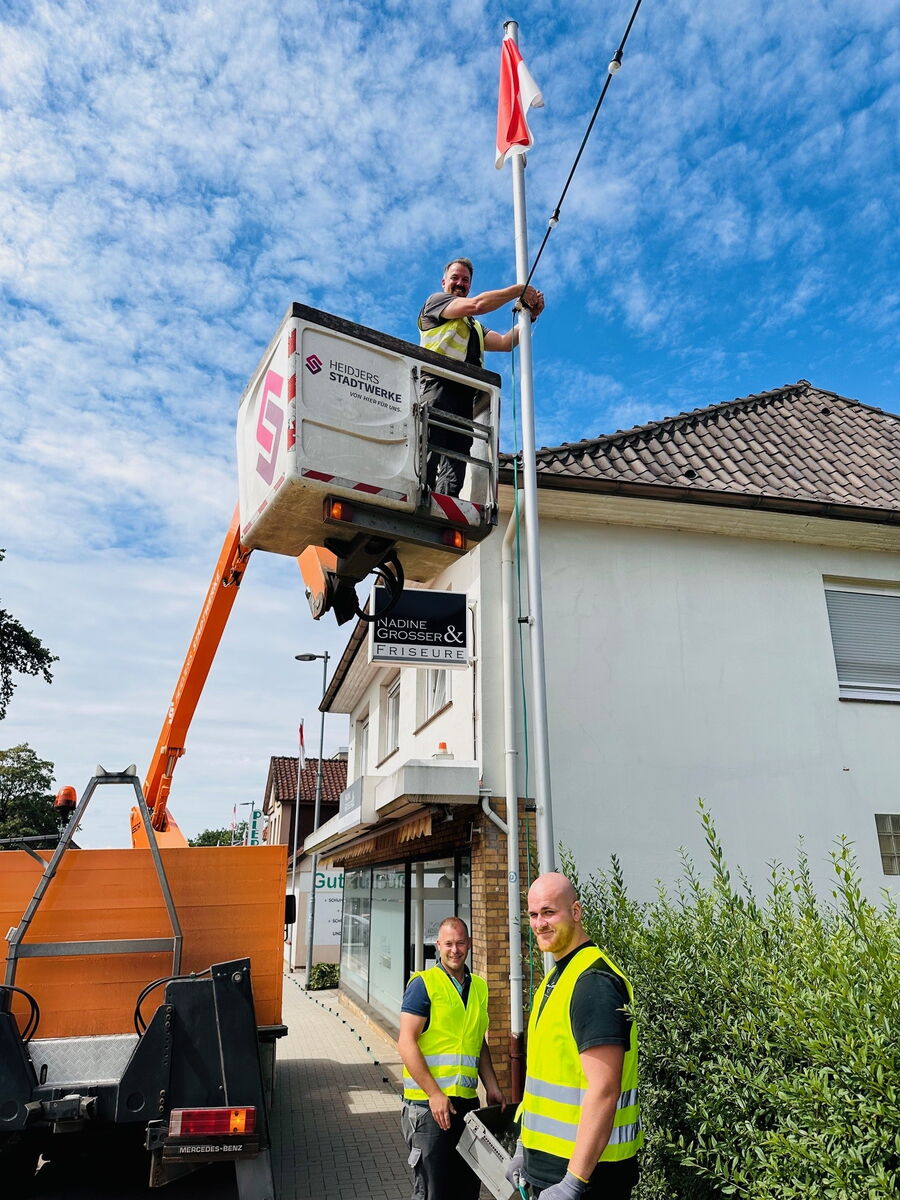 Drei Monteure der Heidjers Stadtwerke schmücken das Heideblütenfest mit energiesparenden LED-Lichterketten.