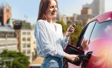 Lachende Frau tankt ihr Elektrofahrzeug