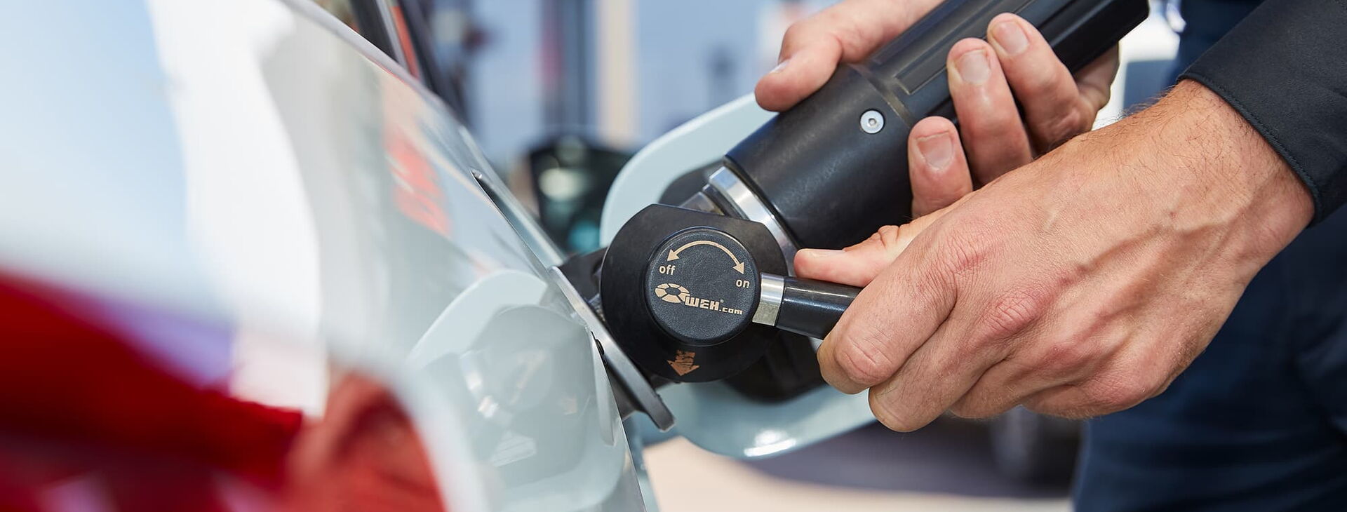 Nahaufnahme eines Tankvorgangs von einem Erdgasauto. Ein Mann hat eine Füllkupplung in die Tanköffnung gesteckt.