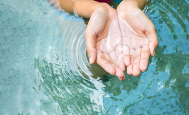 Hände schöpfen Wasser aus einer Quelle