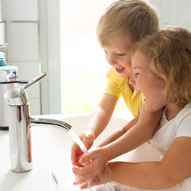 2 Kinder spielen mit dem Wasser im Waschbecken