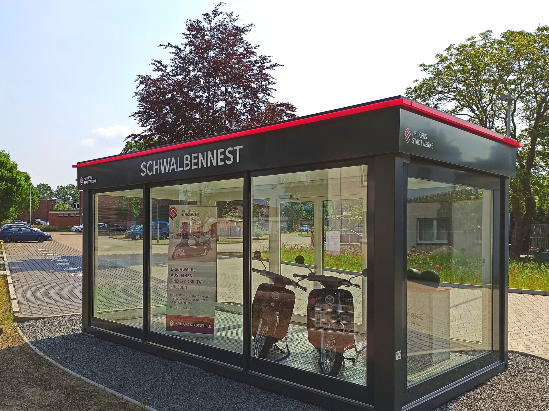 Zwei E-Schwalben sind im Schwalbennest, einem Glascontainer, präsentiert.