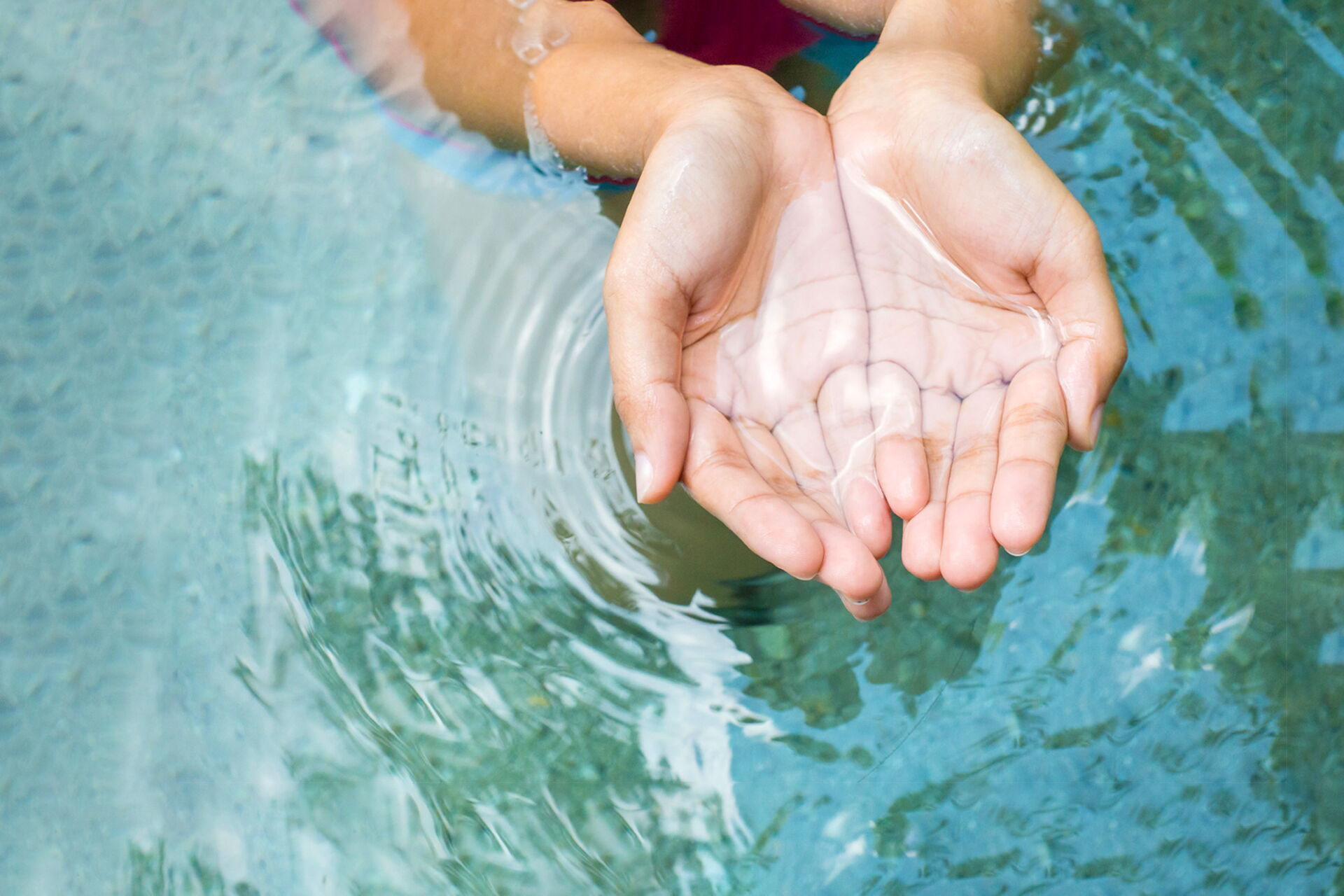 Hände schöpfen Wasser aus einer Quelle