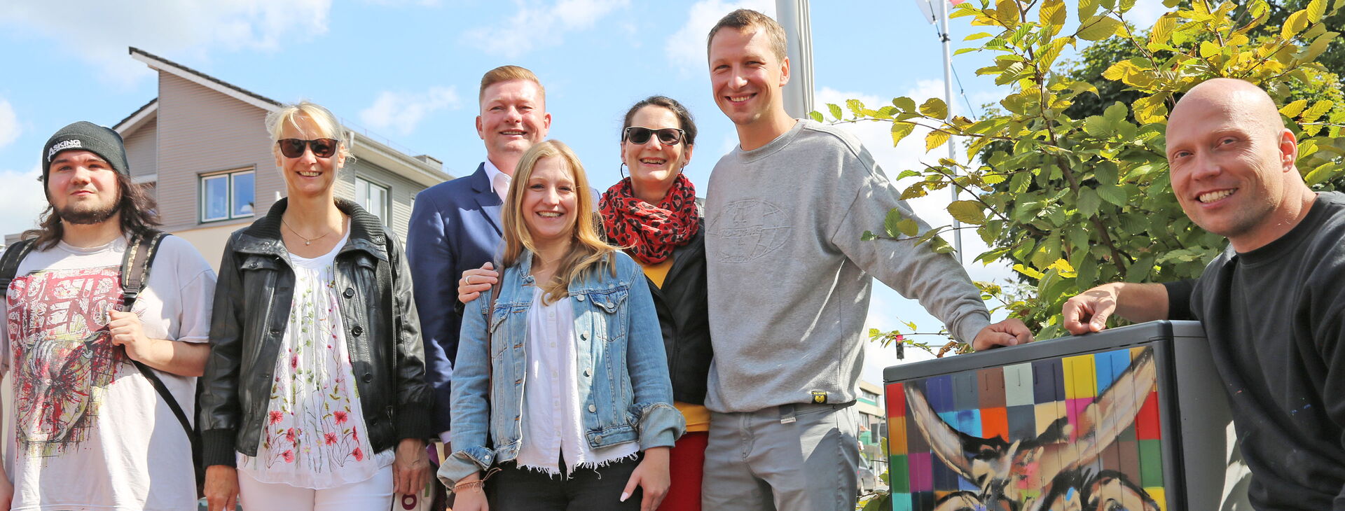 Ein Gruppenfoto mit 7 Personen neben einem angemaltem Kabelverteiler-Schrank