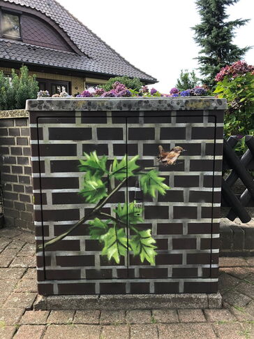 Ein Kabelverteiler-Schrank der mit dem Muster und den Farben der Mauer hinter ihm angemalt wurde