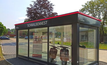 Zwei E-Schwalben sind im Schwalbennest, einem Glascontainer, präsentiert.