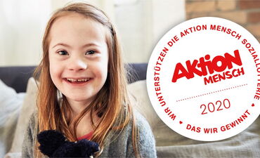 Ein Mädchen das auf einem Sofa sitzt, schaut in die Kamera und lächelt. Da neben steht das Aktion Mensch Logo von 2020